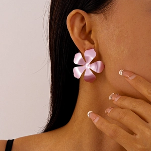 Detailed view of pink flower stud earring with metallic matte finish on model