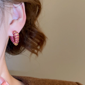 Gros plan sur les boucles d'oreilles cœur en or 18k et ruban bordeaux sur modèle