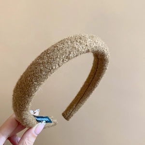 Close-up of brown plush fabric headband with handmade tag and soft wool texture