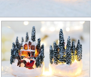 Macro shot of glowing Christmas resin house decor with snowy pine trees and warm light