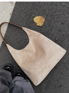 Minimalist beige suede tote bag with brown leather straps in an autumn outdoor setting