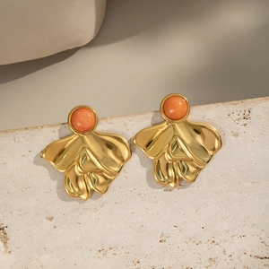 Detailed close-up of vintage geometric gold earrings with round orange gemstone inlay