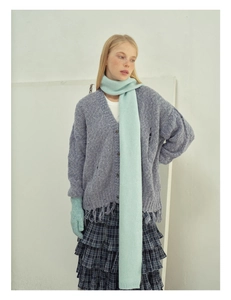 Detailed knit texture of wool blend scarf paired with purple cardigan and plaid skirt