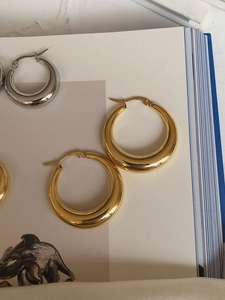 Close-up of gold and silver oval hoop earrings on an open artistic book background