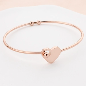 Rose gold interlocking heart bangle made of stainless steel with a minimalist pendant