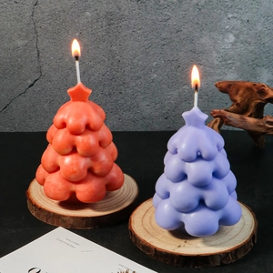 DIY Christmas tree scented candles in orange and purple with star tops on wood base