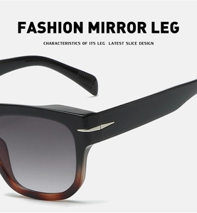 Detail of black and amber frame sunglasses featuring unique silver metal arrow hinge