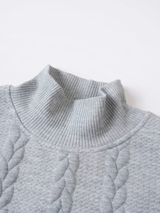 Close-up of grey cable-knit turtle neck sweater showing detailed texture and ribbed collar