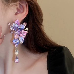 Close-up of statement purple flower earrings with sparkling rhinestones and teardrop crystals