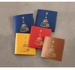 Flat lay of colorful 3D birthday cards with gold foil cake designs on textured paper