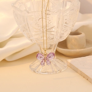 Macro detail of butterfly pendant with purple crystals and gold chain on silk