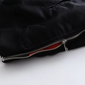 Detail der Bomberjacke mit schwarzem Nylon, Metallreißverschluss und hellem orangefarbenem Futter