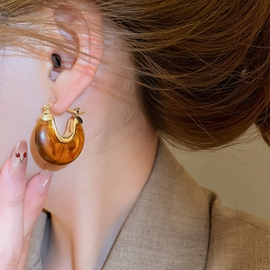 Gros plan de boucles d'oreilles vintage en forme de U avec résine texturée ambrée