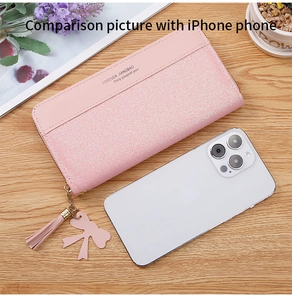 Pink glitter long wallet size comparison with a smartphone on a rustic wooden table