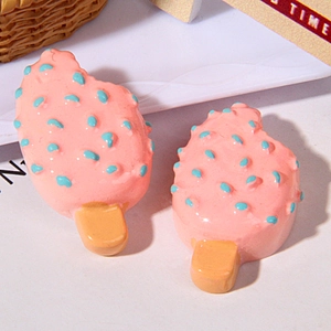 Close-up of pink resin popsicle charms with blue dots for DIY phone case crafts
