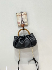 Detail of black pleated cloud bag with round wood-grain handle and metal chain strap