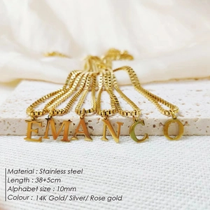 Close-up of stainless steel alphabet necklaces with 38+5cm chain on white stone display