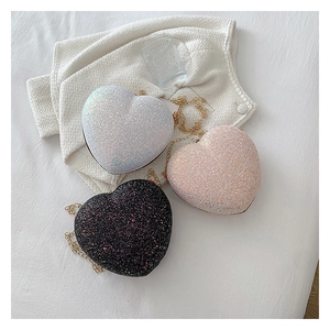 Detailed view of heart-shaped glitter crossbody bags in white, pink, and black colors