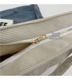 Détail de la fermeture éclair dorée sur le sac fourre-tout en velours côtelé beige doux