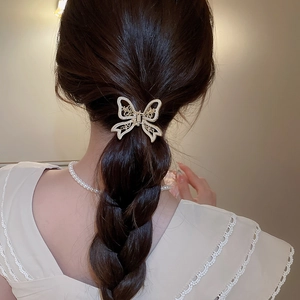 Elegant gold butterfly hair claw with pearls shown worn on a woman's hair in a stylish look