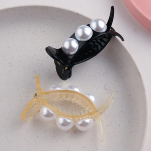 Detail of black and amber hair claw clips with large pearls and non-slip inner teeth