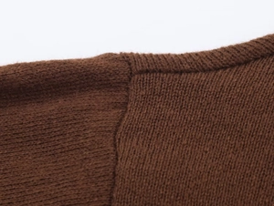 Detailed close-up of the shoulder stitching and neckline on a brown knit sweater