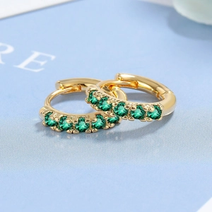 Elegant gold hoop earrings with green zircon stones set against a textured blue background