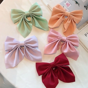 Close-up of five colorful oversized satin bow hair clips with elegant long ribbons