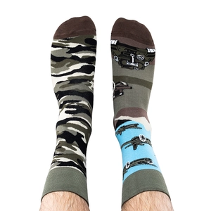 Detail view of asymmetric socks with green camouflage and cartoon military vehicle patterns