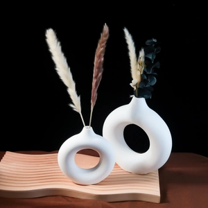 Macro di due vasi in ceramica bianca a forma di ciambella su base in legno decorativa
