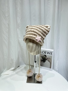 Detail of striped cat ear knit beanie with pink stars and fluffy pom-pom earflaps