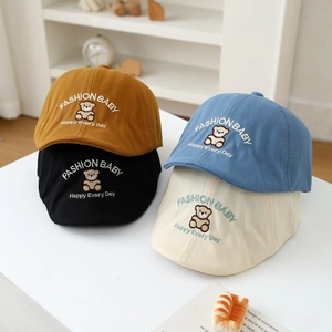 Detail of four colorful baby bear embroidery beret hats in yellow, black, blue and beige