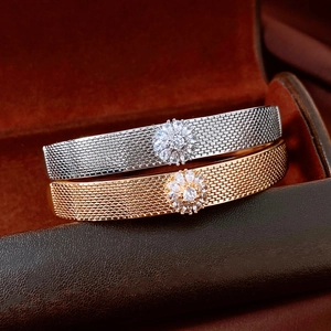 Detail of 18K gold and silver braided bracelets with floral zircons on leather box