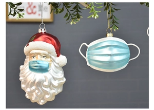 Dettaglio di ornamenti natalizi con Babbo Natale e mascherina medica per l'albero