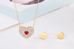 Close-up of gold heart necklace with red gem and matching earrings on a magazine