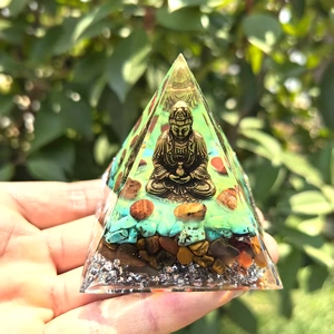 Close-up of a handmade crystal Orgone pyramid with gold Buddha and healing stones