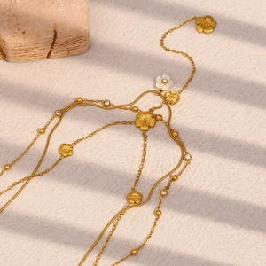 Detailed close-up of a multi-layer 18K gold-plated floral belly chain on a stone background