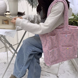 Detail of pink plush tote bag with multi-pockets and colored buttons in snow scene