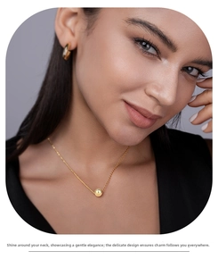 Close-up of a minimalist gold pendant necklace featuring a polished sphere with a zircon stone
