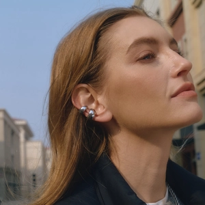 Close-up of a chunky silver stainless steel ear cuff worn on a model in sunlight