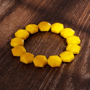 Detail of bohemian yellow hexagonal crystal beads with amber-like texture on wood background