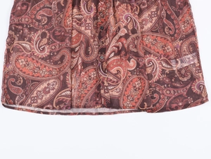 Detail of bohemian paisley chiffon shirt hem with reddish brown patterns and buttons