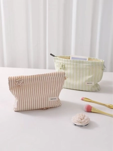 Beauty case a righe rosse e verdi con ciondoli decorativi su una scrivania bianca pulita