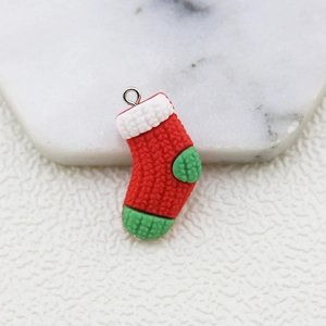 Macro detail of a resin Christmas stocking charm with red, white and green knit texture