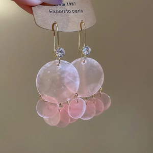 Detail of pink shell tassel earrings with zircon studs and golden geometric accents