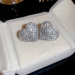 Macro shot of silver heart stud earrings with cubic zirconia pavé in a white jewelry box