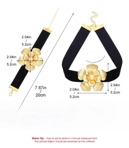 Dettaglio di choker in velluto nero con grande fiore dorato e perla bianca incastonata