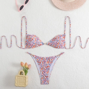 Flat lay of pink floral bikini with gold and pearl accents on white textured background