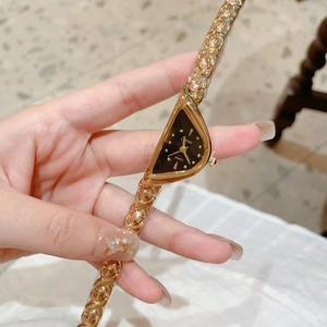 Gros plan d'une montre dorée triangulaire unique avec cadran noir et bracelet chaîne