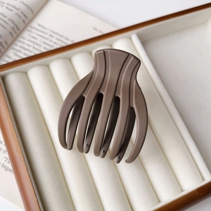 Close-up of a matte brown large shark hair claw clip in an elegant jewelry box setup